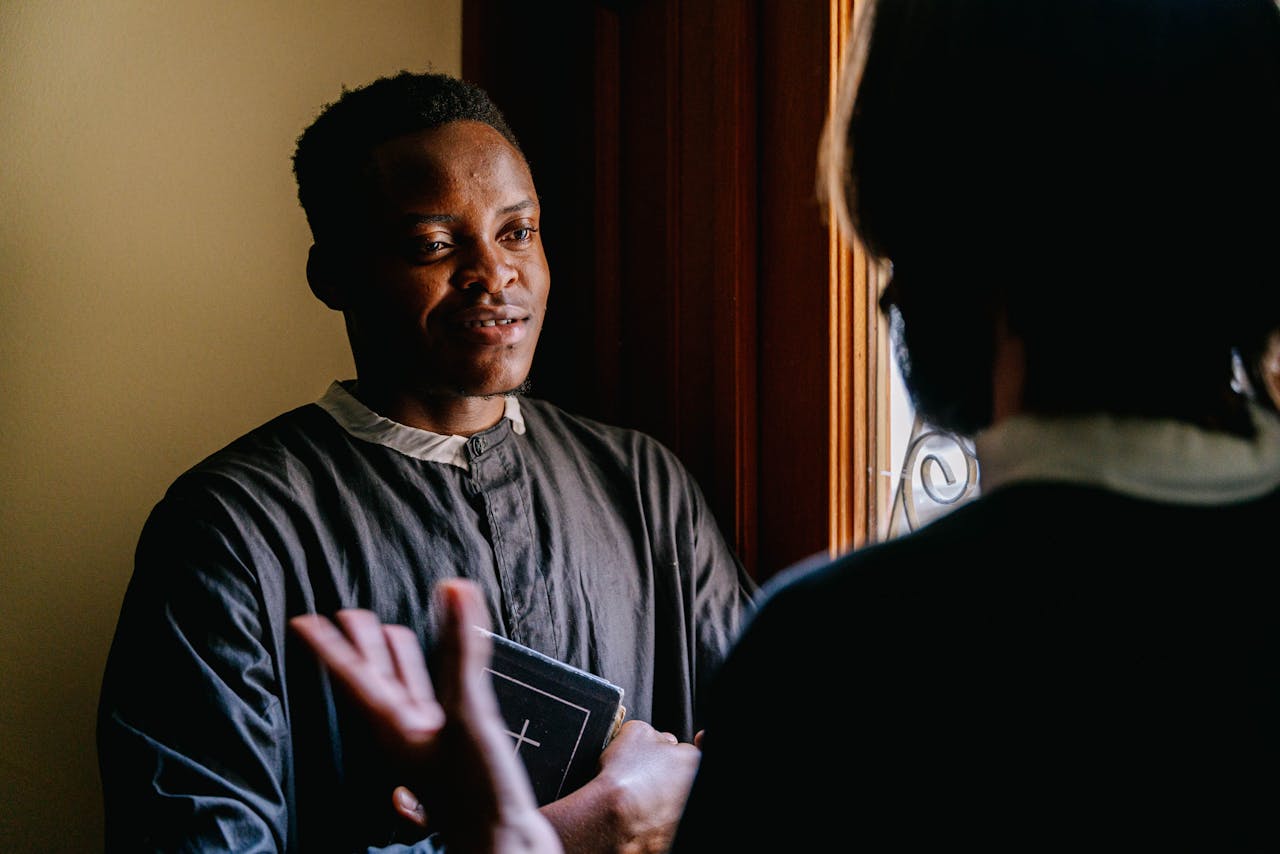 Two seminarians discussing religious teachings with a Bible in hand, bathed in natural light.